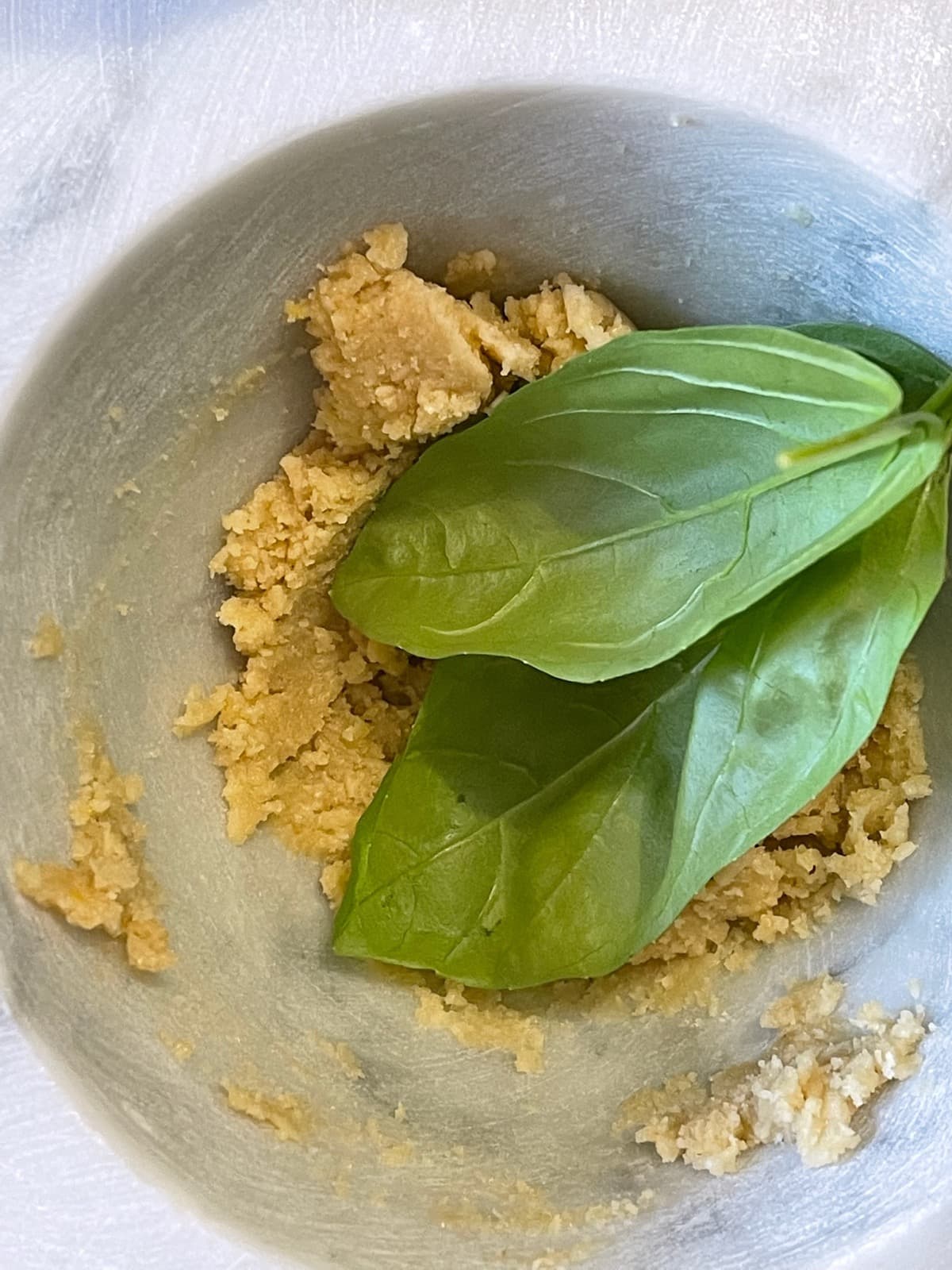 Pesto genovese nel mortaio con foglie di basilico fresco